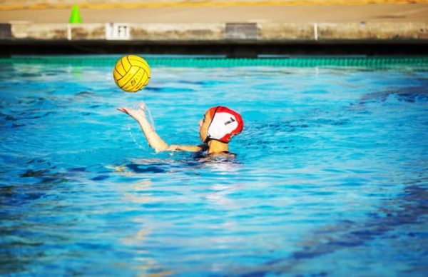 Varsity girls water polo player Alex Christensen putting the ball into play.