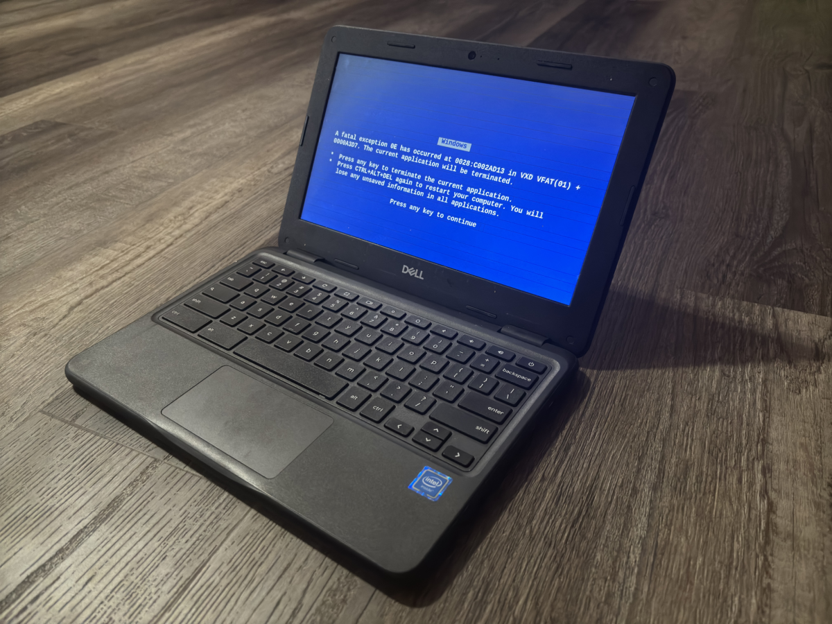 Black Chromebooks sits on dark wooden floor with blue background displayed on screen